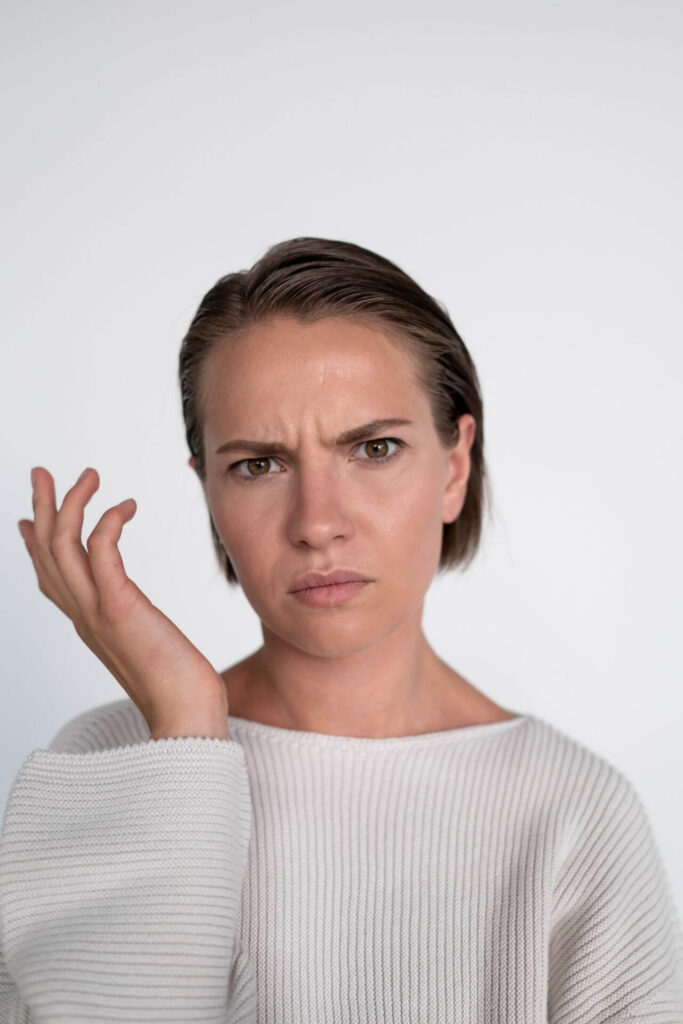 Confused woman with short hair and beige sweater. Discover how functional medicine in Orland Park, IL can help you heal from your PMOS symptoms.