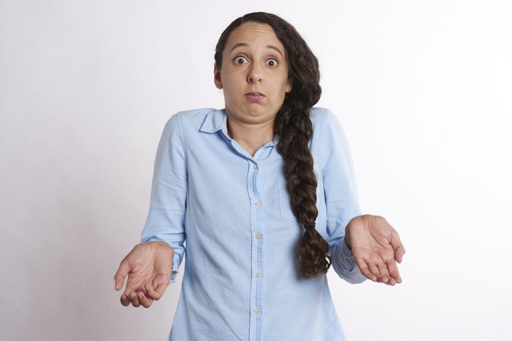 Confused woman with a long braid wearing a blue collared shirt holding her hands out. Learn why your PMOS symptoms are disrupting your life and how functional medicine in Orland Park, IL can fix them.