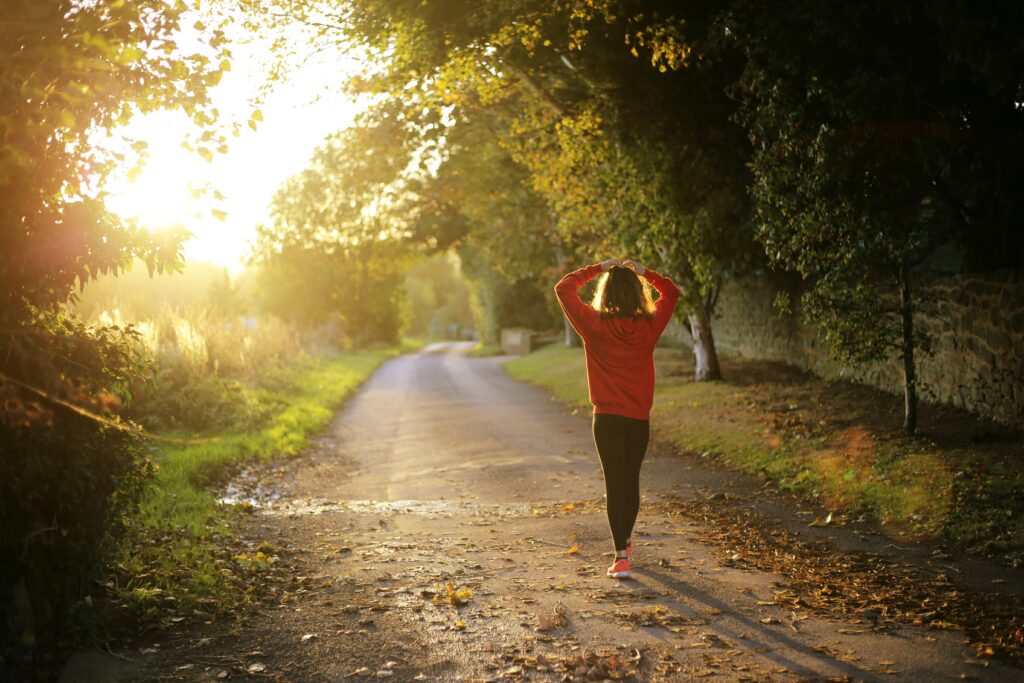 Woman walking on a sunlit path in Orland Park, IL to improve her health and wellbeing.
