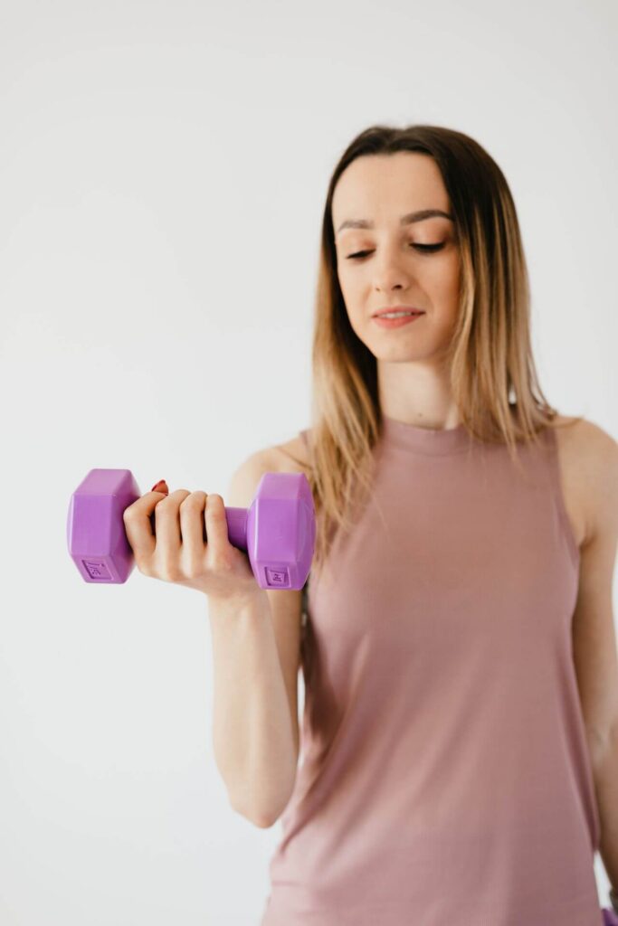 Happy woman lifting a pink weight. Begin to manage your low t symptoms with the help of functional medicine in Orland Park, IL.
