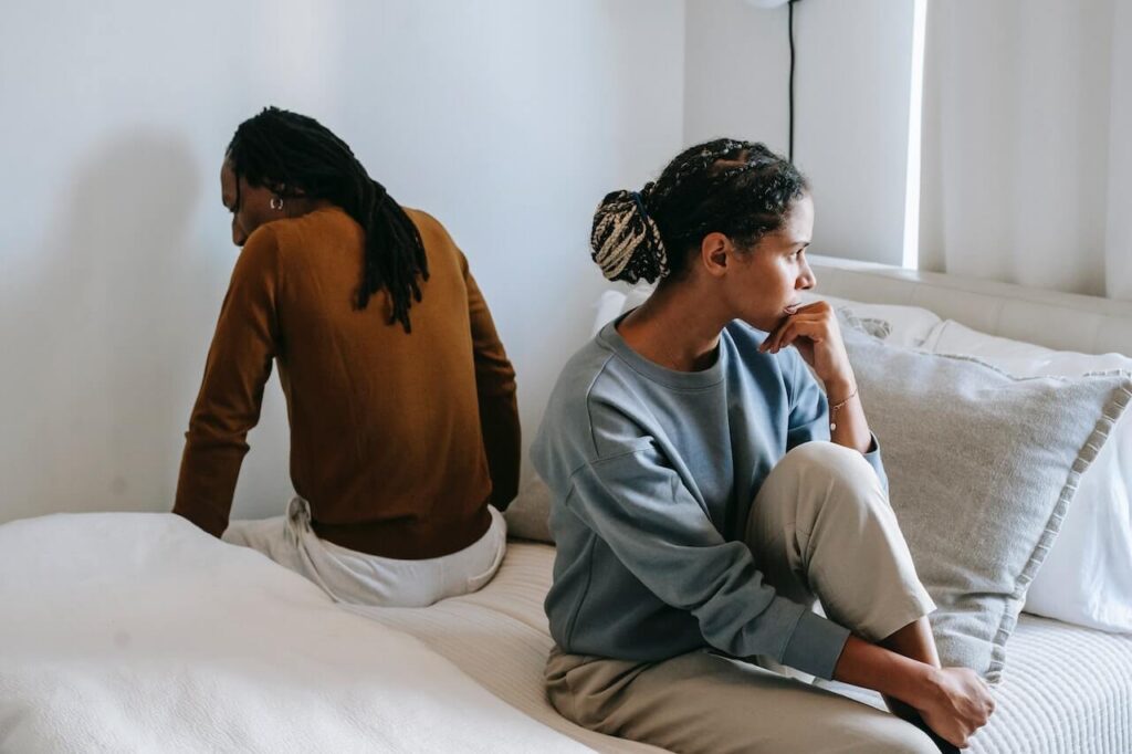 Couple sitting on a bed facing away from each other showing distance. If you're a woman with low testosterone discover how a functional medicine doctor in Orland Park, IL can help you.